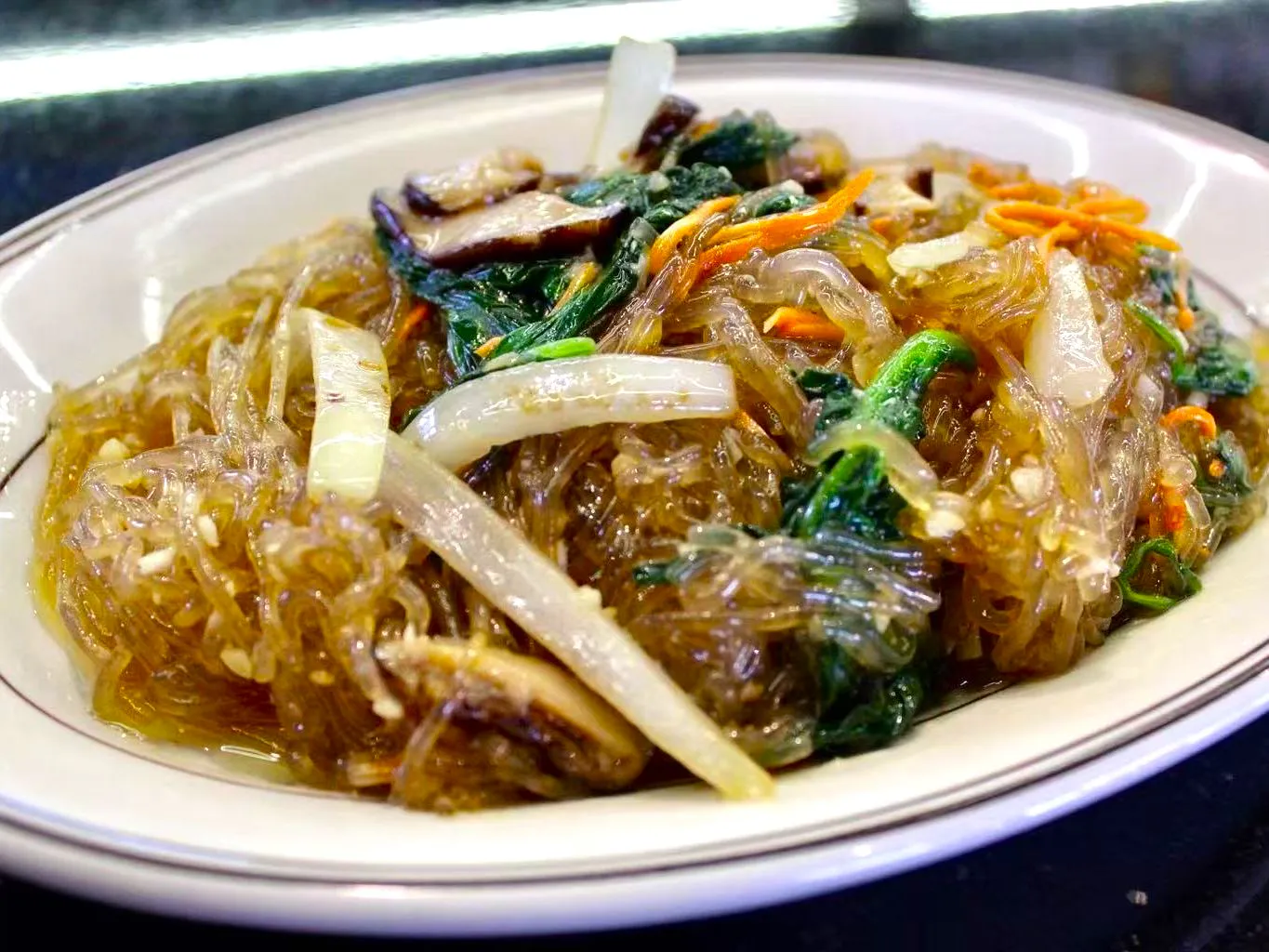 Korean stir-fried glass noodles mixed with mushrooms and leafy greens at FirePot Korean BBQ & Hot Pot, an Asian Restaurant in Grand Forks