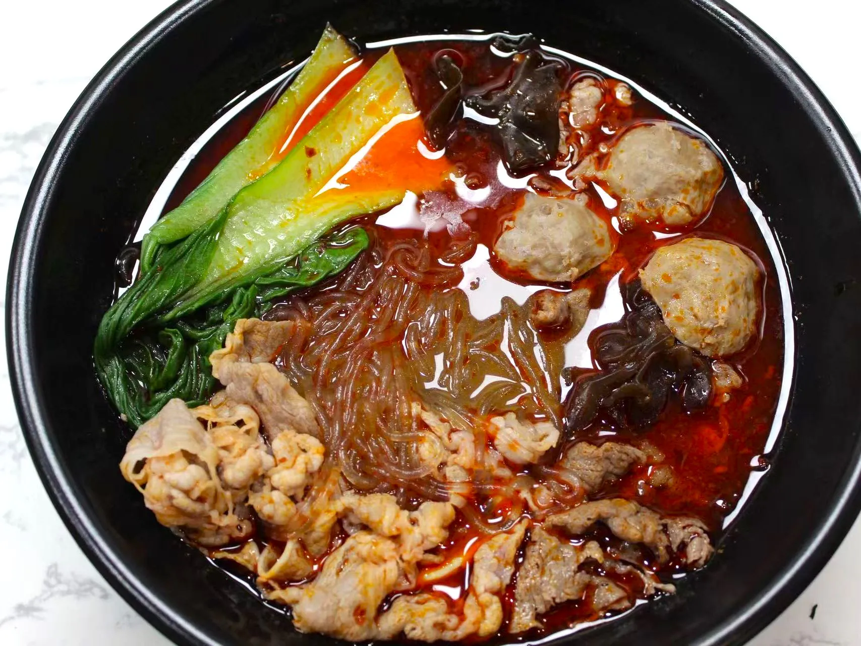 Spicy red broth glass noodle soup with beef, meatballs and bok choy at FirePot Korean BBQ & Hot Pot, an Asian Restaurant in Grand Forks