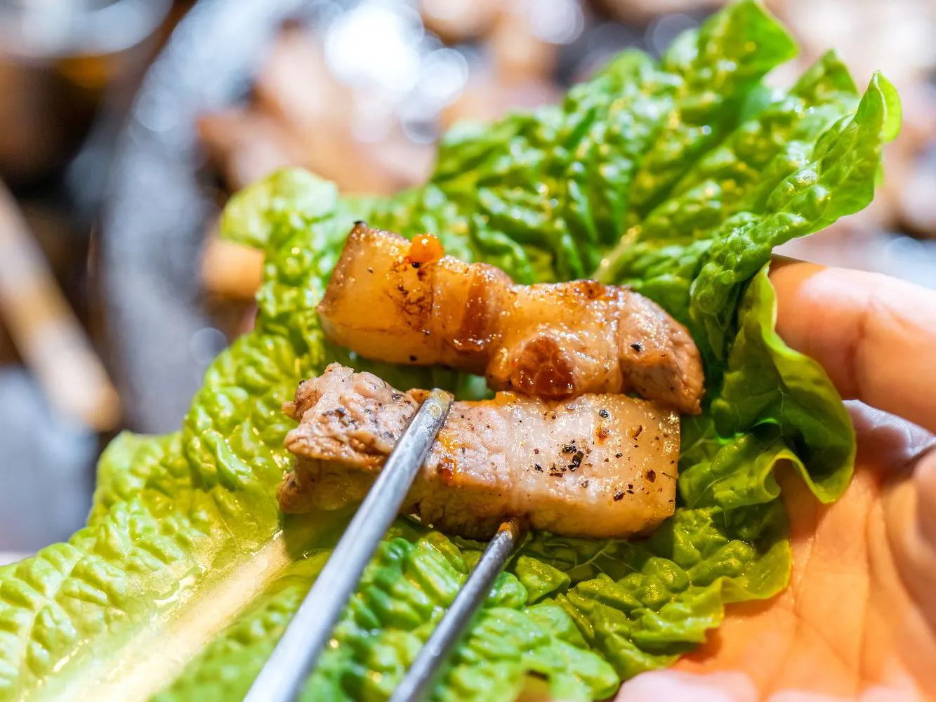 Grilled pork belly pieces laid on fresh green lettuce leaves at FirePot Korean BBQ & Hot Pot, an Asian Restaurant in Grand Forks