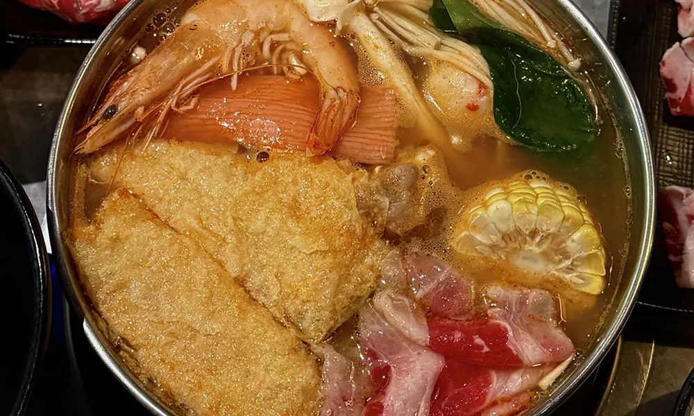 Seafood hot pot featuring whole shrimp, fried tofu, corn and pork belly in light broth at FirePot Korean BBQ & Hot Pot, an Asian Restaurant in Grand Forks