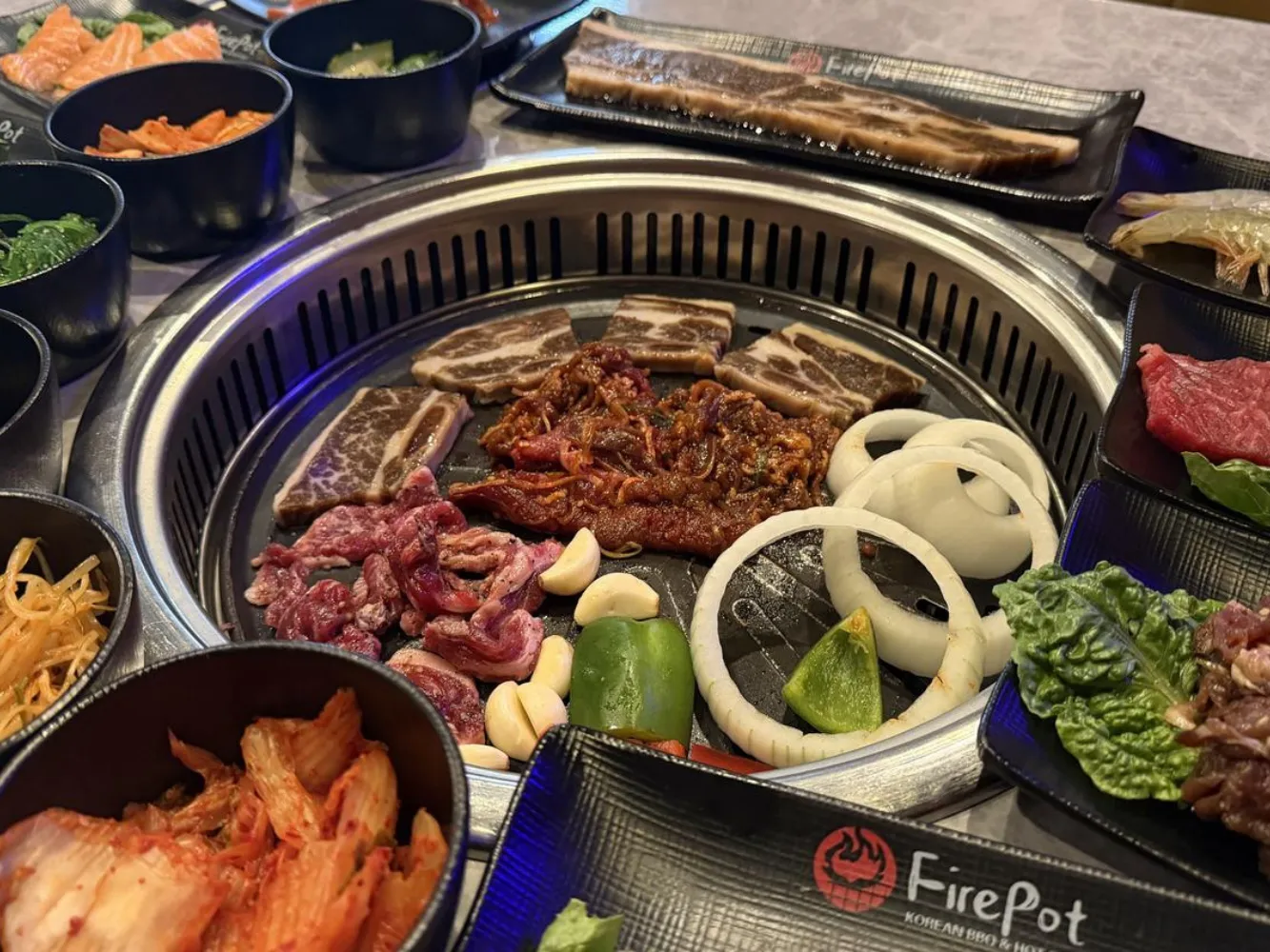 Varied marinated meats and vegetables cooking on grill at FirePot Korean BBQ & Hot Pot, an Asian Restaurant in Grand Forks