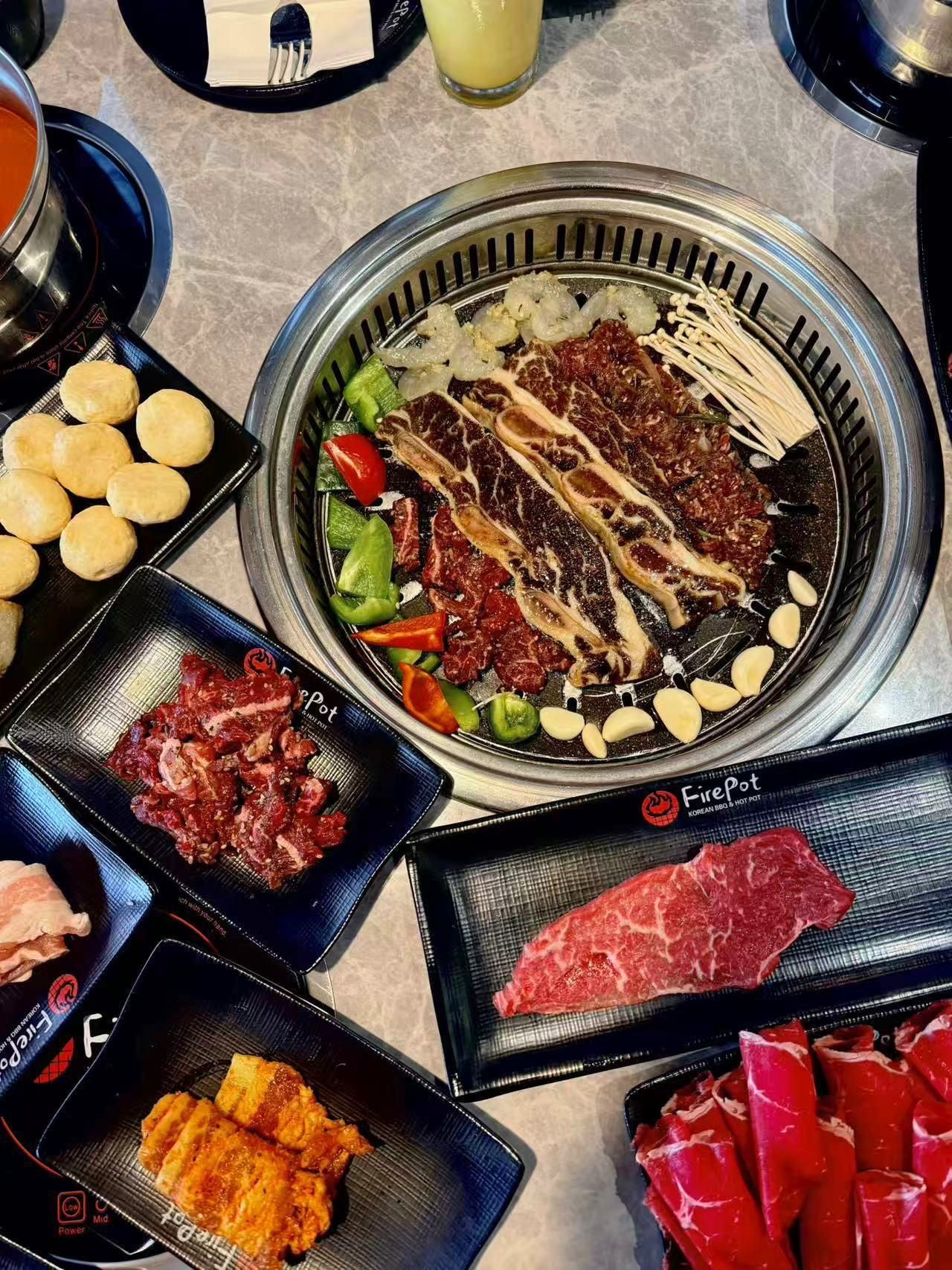 Full spread of raw beef, shrimp and side dishes on Korean BBQ grill table at FirePot Korean BBQ & Hot Pot, a Asian Restaurant in Grand Forks
